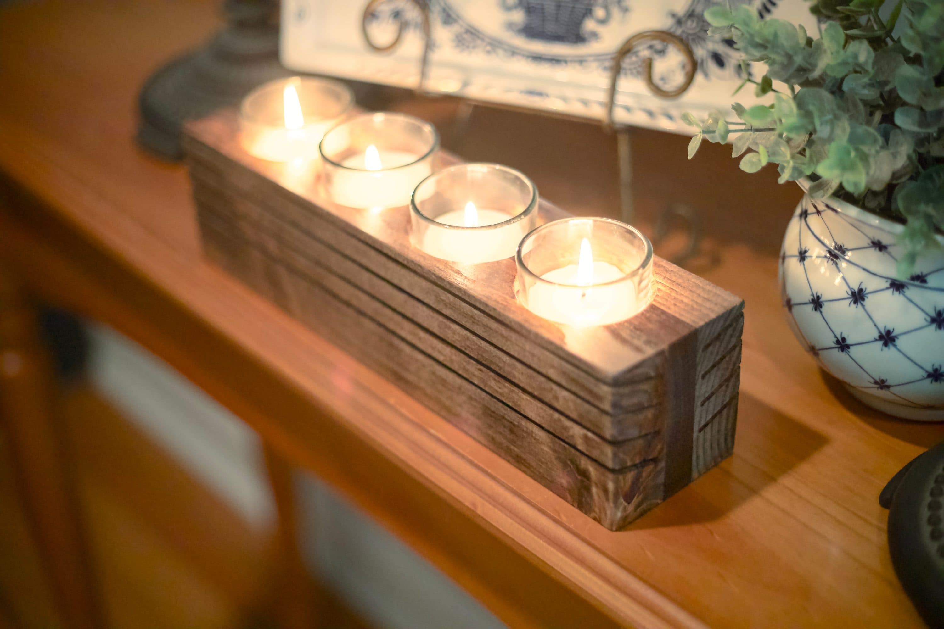 Louvered candle holder lit on a sideboard